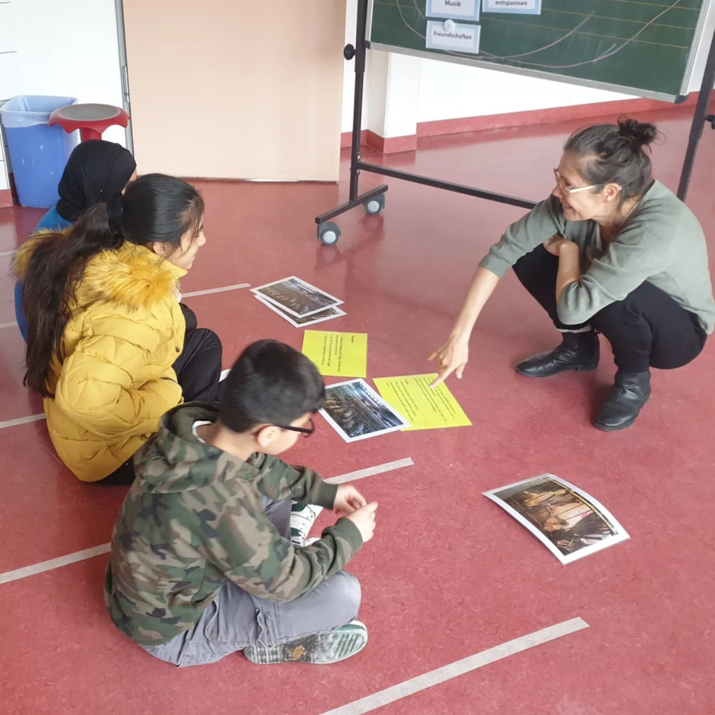 Das Bild zeigt drei Kinder und eine unsere Moderierenden in einem Workshop.